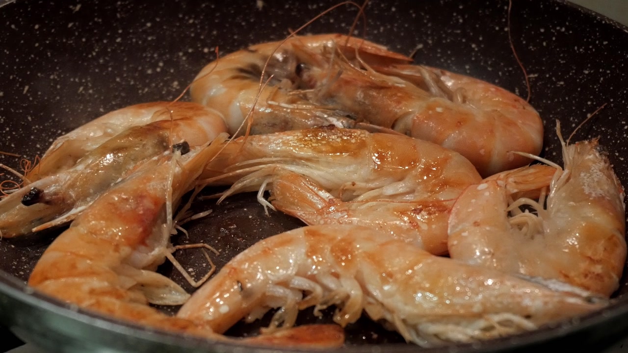 Fresh king prawns sizzling in a pan, savory cooking process