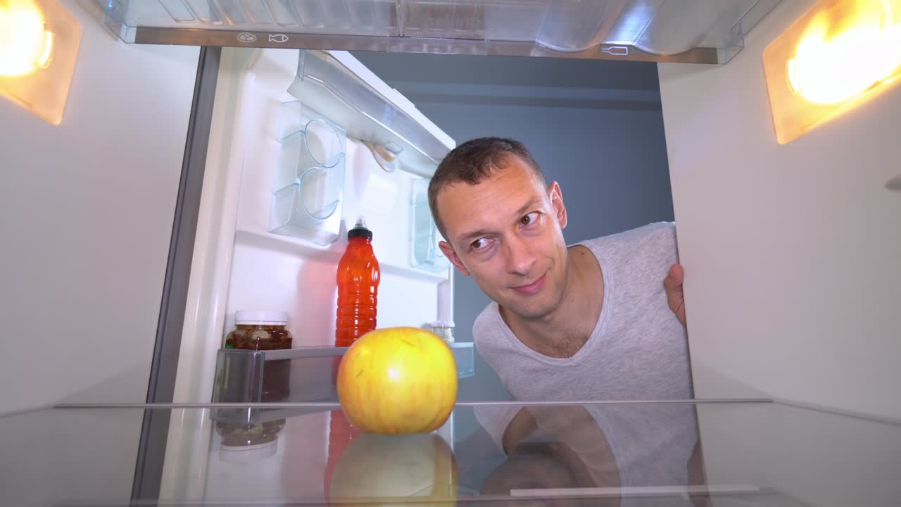 el tipo abre el refrigerador en el que sólo hay una manzana.