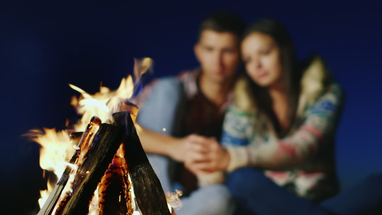 불타는 불 속에서 부드럽게 이야기하는 로맨틱 커플