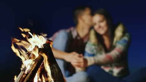 pareja romántica hablando suavemente en el fuego ardiente nitidez en el fuego una pareja joven está borrosa
