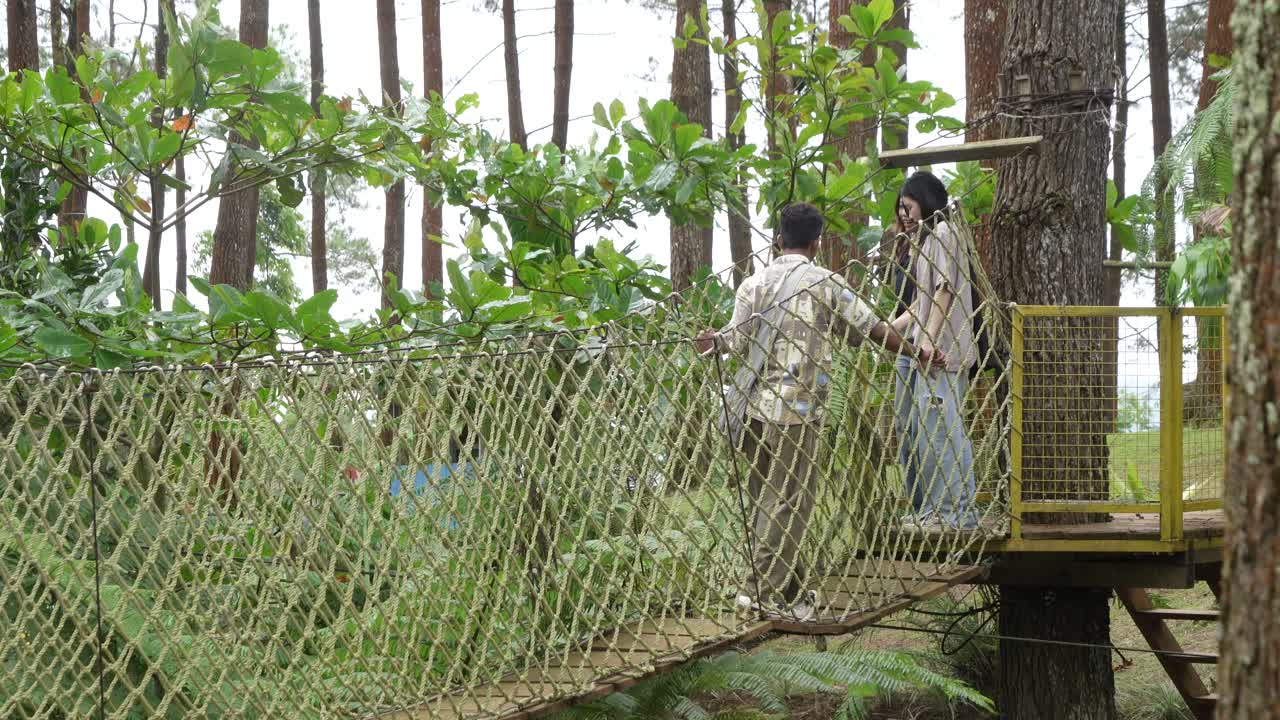Young Asian Friends Crossing Rope Bridge in Forest Adventure