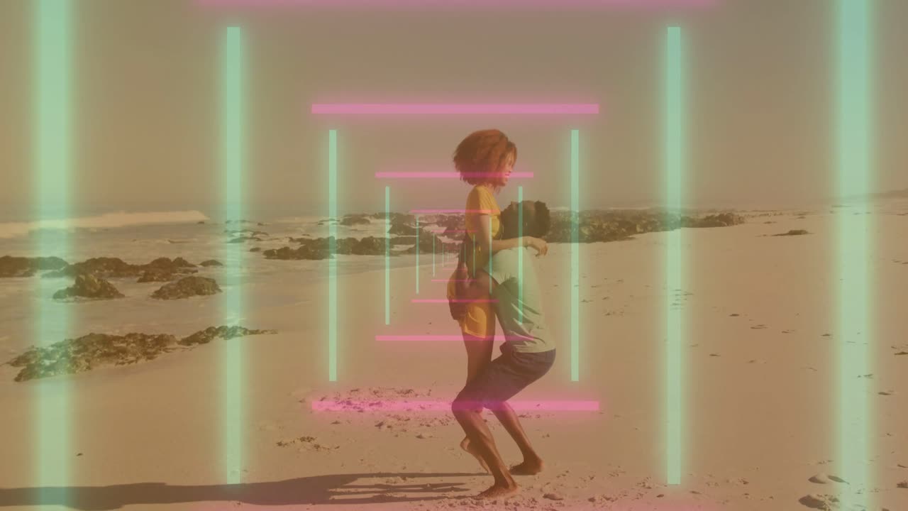 Video verticale: Una donna in vestito giallo che si tiene per mano e stuzzica un uomo che la solleva sulla spiaggia, con un effetto neon in sovrapposizione.