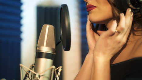 beautiful woman in headphones records a song in a professional recording studio. face close-up