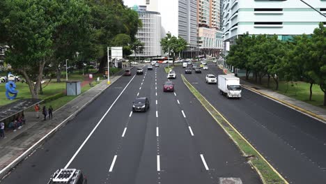 A-busy-street-in-Panama-City,-Panama,-lined-with-trees-and-a-skyline-of-tall-buildings