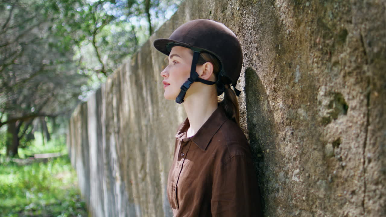 Dreamy woman jockey standing outdoor. mare resting in field pasture