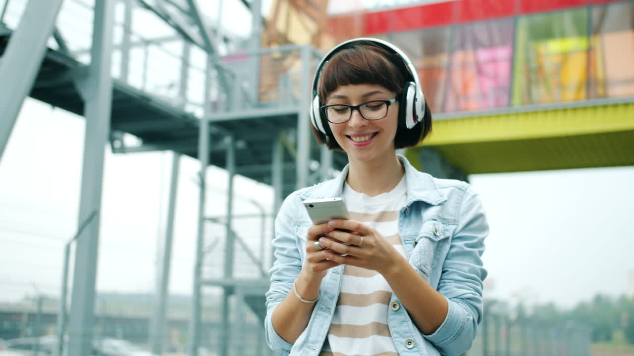 Young woman using smartphone with headphones outdoors