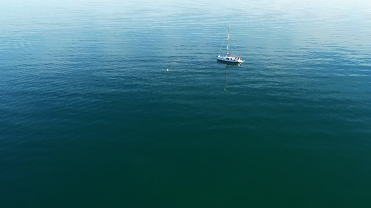 태양광 을 반사 하는 깊은 파란 물 에  ⁇ 어 있는 요트 를 향 한 공중 도리