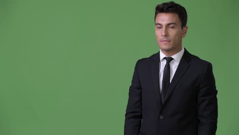 young handsome hispanic businessman against green background