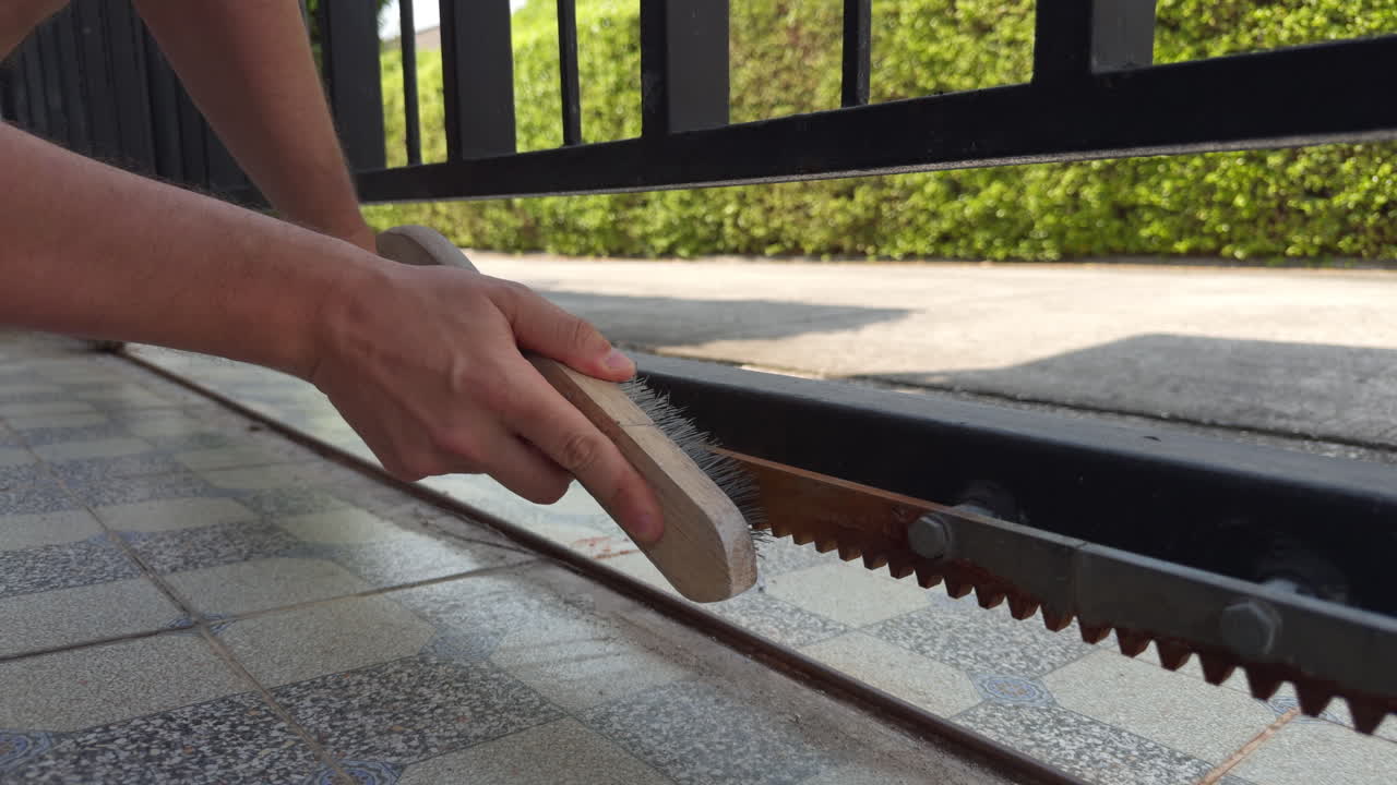 Close up of hands removing rust from metal gate using wire brush. Maintenance and cleaning process ideal for repair, DIY, renovation and industrial content