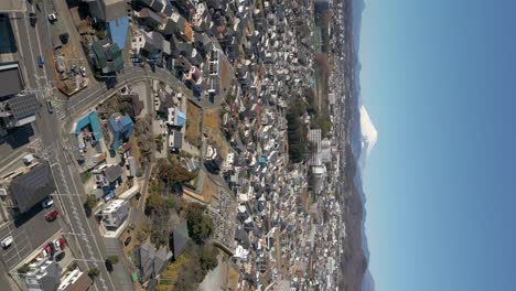 vertical drone flight over typical japanese suburban city at bottom of mt