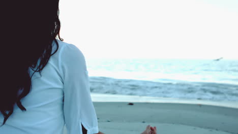 mujer practicando yoga en la playa