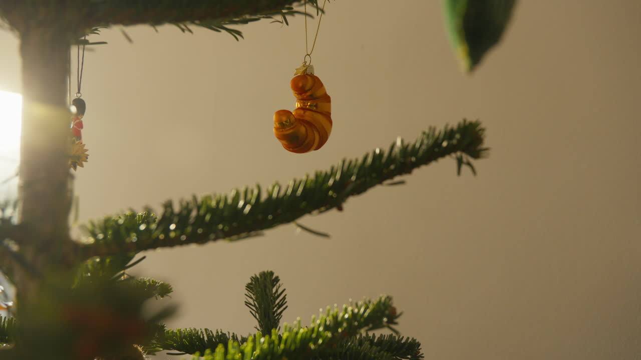 un ornamento de croissant dorado colgando de un frondoso árbol de navidad