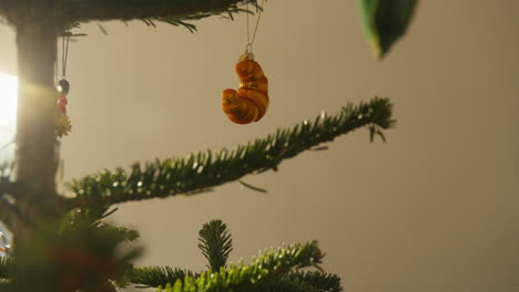 Adorno-De-Croissant-Dorado-Colgando-De-Un-Exuberante-árbol-De-Navidad.