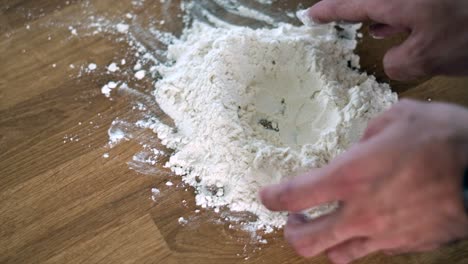 man's hands carefully making a hole in flour mound