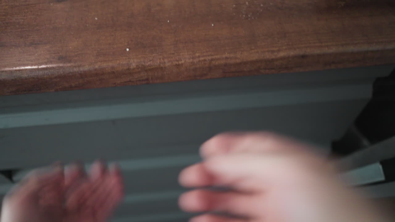 POV of opening a wooden cutlery drawer in a kitchen revealing spoons, forks, knives, with a hand-held camera motion blur effect