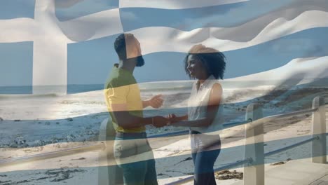 animación de la bandera de grecia sobre una pareja afroamericana en la playa