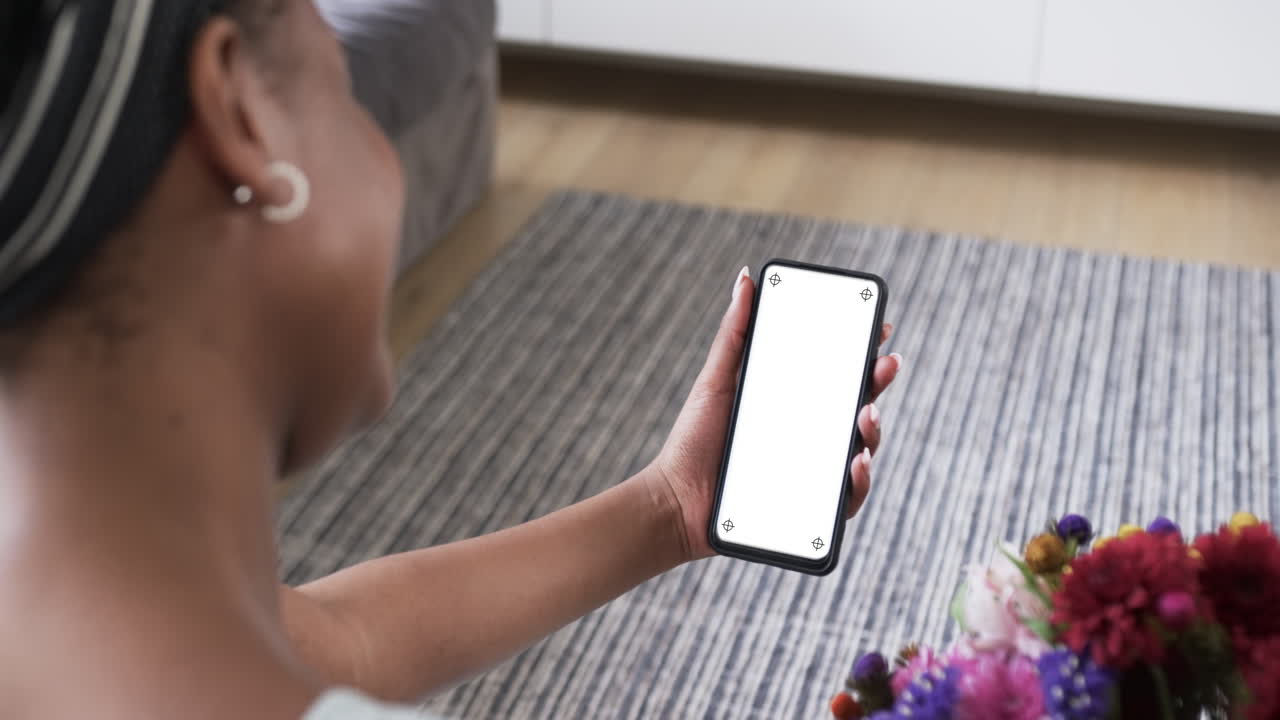 Mujer afroamericana sosteniendo un smartphone con espacio para texto en la pantalla en blanco.