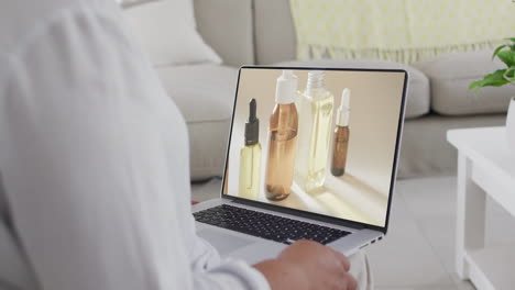 biracial woman using laptop at home for online shopping, slow motion