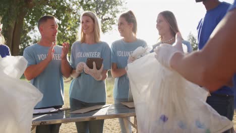 mid adults volunteering and woman taking notes during river clean-up day