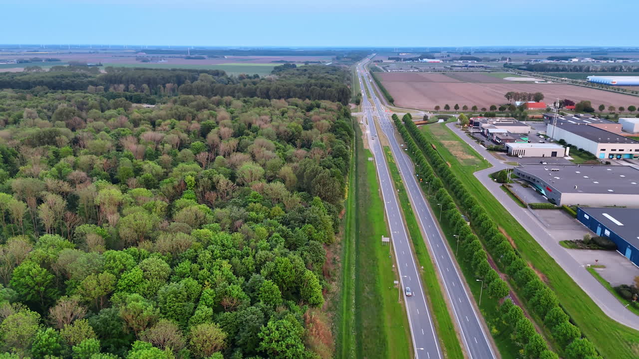 Highways along the green forest and storehouses. Aerial perspective on the countryside in the Netherlands.