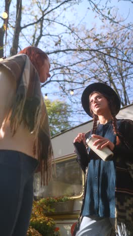 two women having a conversation outside a vintage van on a sunny autumn day.