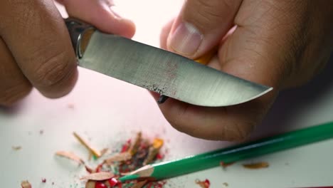 beelden van handen die langzaam een potlood slijpen en wat kleurpotloden met een scherp mes