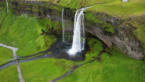 iconic iceland waterfall with green nature around, aerial drone view