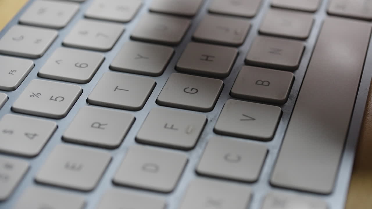 Macro shot of a single hand typing on a silver computer keyboard. Ideal for technology, remote work, and digital accessibility concepts