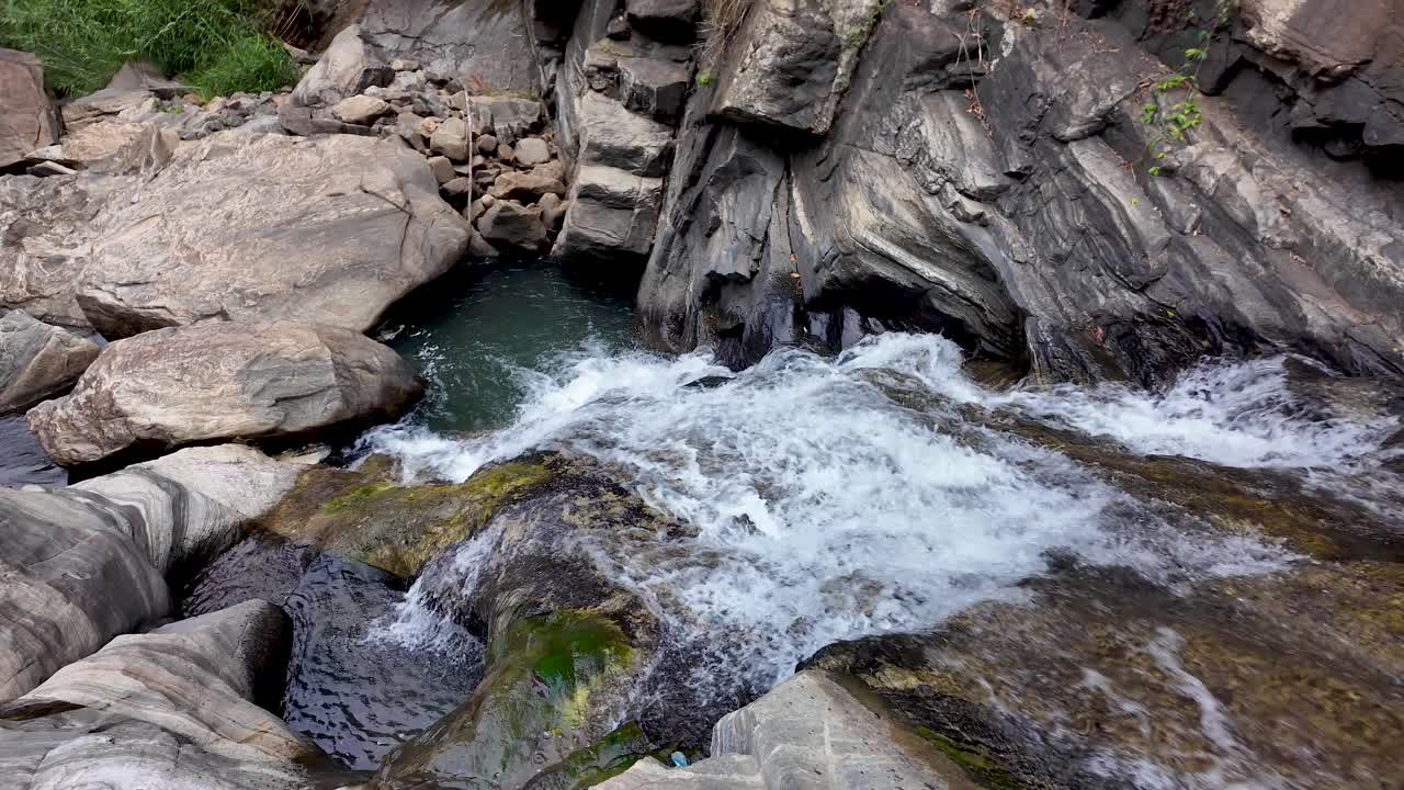 Waterfall cascades over rugged rocks, surrounded by nature's beauty. The flowing water creates a peaceful atmosphere, showcasing the raw and powerful elements of a pristine landscape.