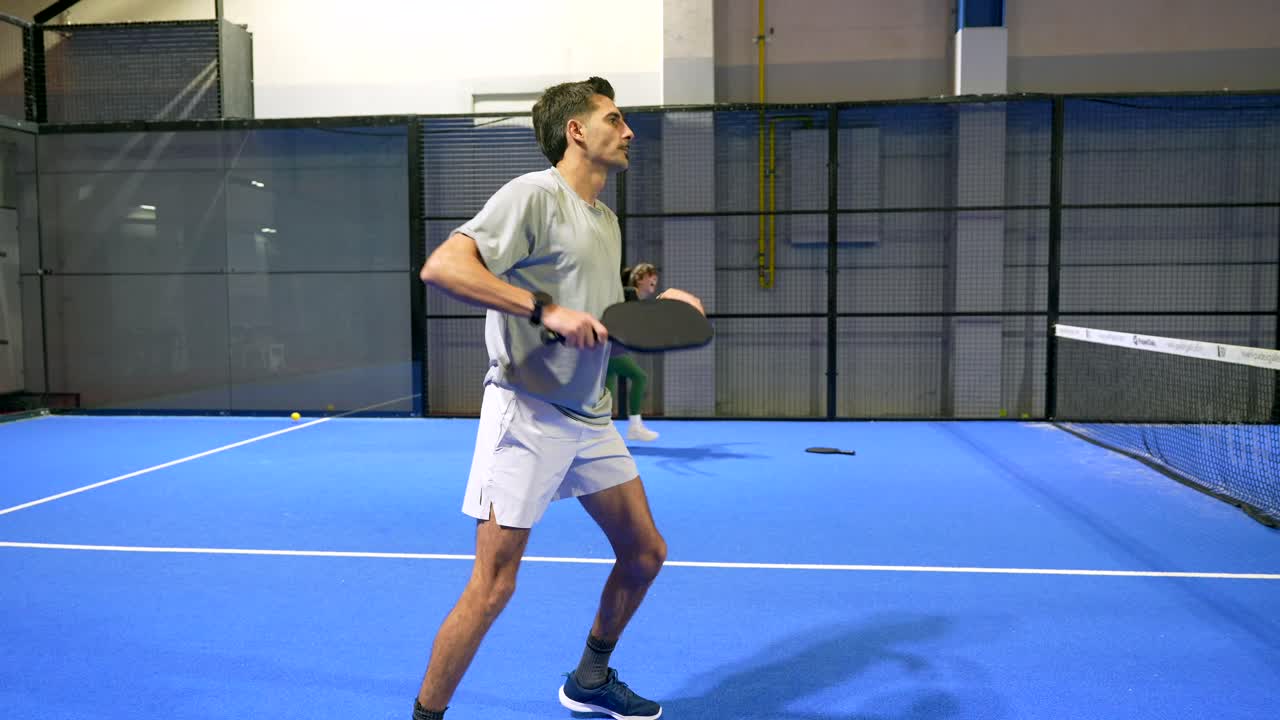 Man and Woman Playing Padel Tennis on an Indoor Court