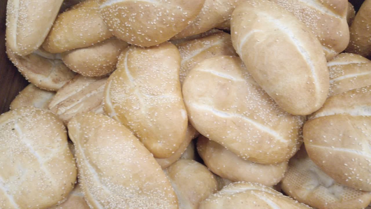 Pan left shot of fresh bread loaves stacked at bakery counter with natural light