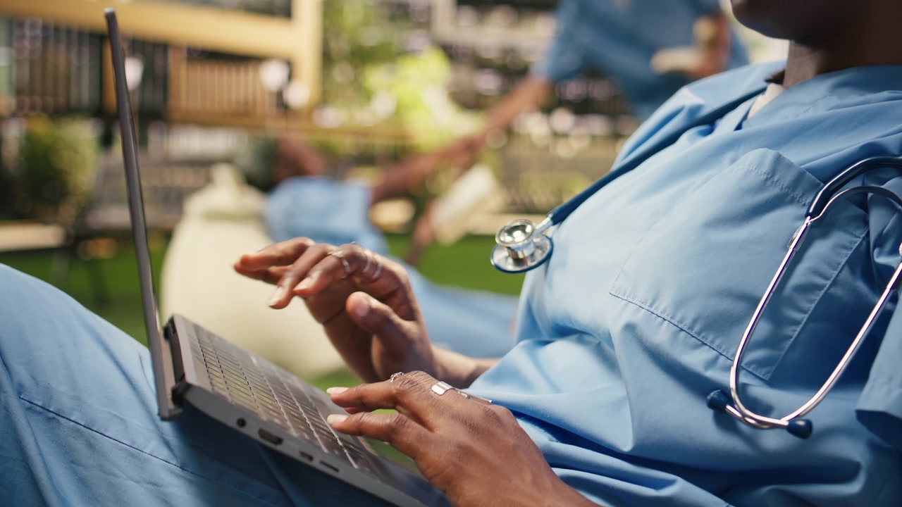 Close up of medical student typing on laptop keyboard seated on beanbag