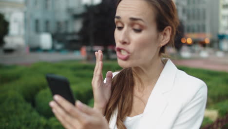 mujer de negocios molesta maldiciendo por llamada de video en el teléfono inteligente en el paseo por la ciudad.