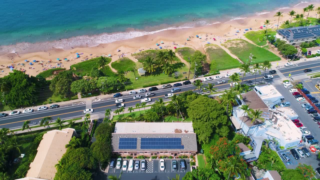 Aerial view tilt upward movement of real estate and wonderful beach shore, green grass on a sunny day in Kihei Akahi, Hawaii Island