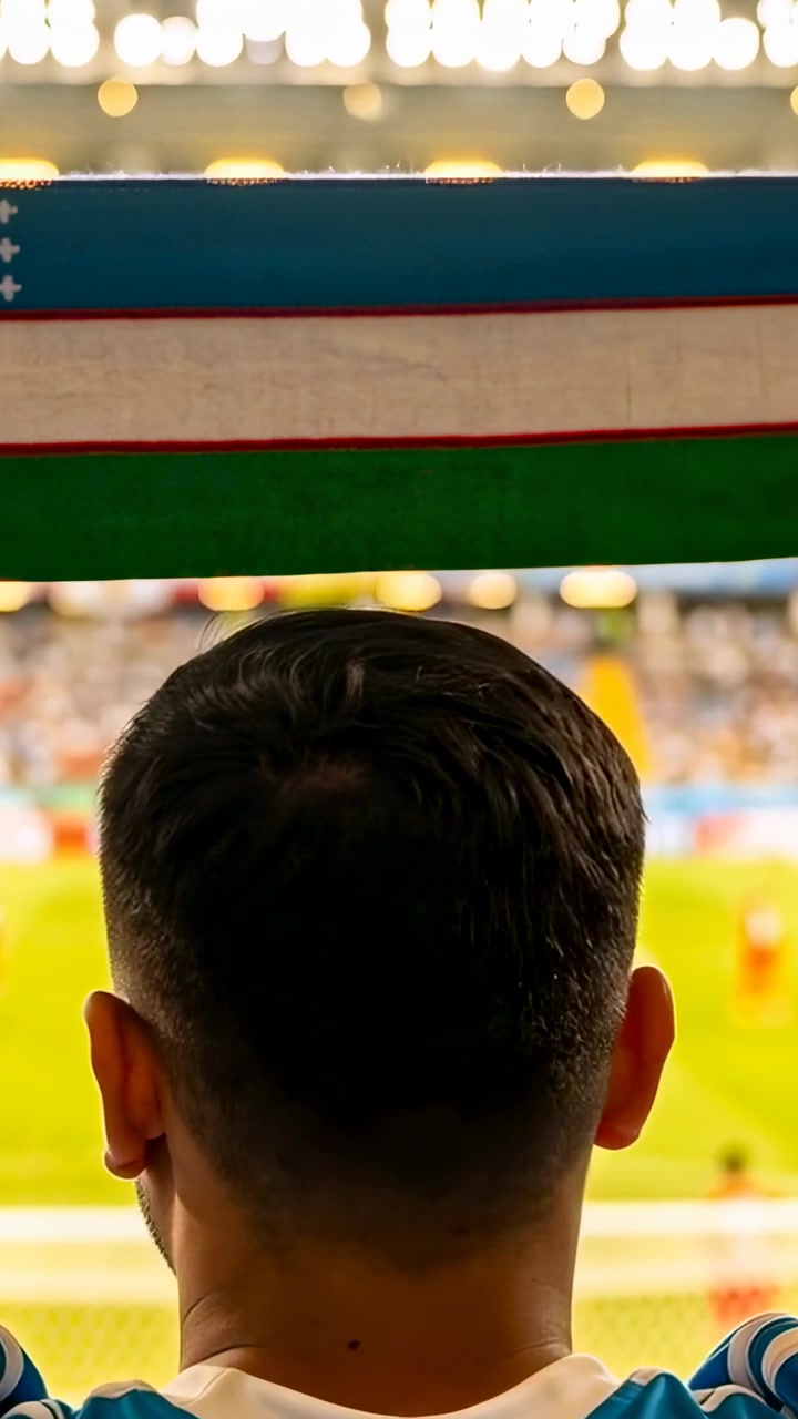 Vertikal video: Mandlig fan vender sig og reagerer på jubel på stadion, iført blå trøje og holder et tørklæde