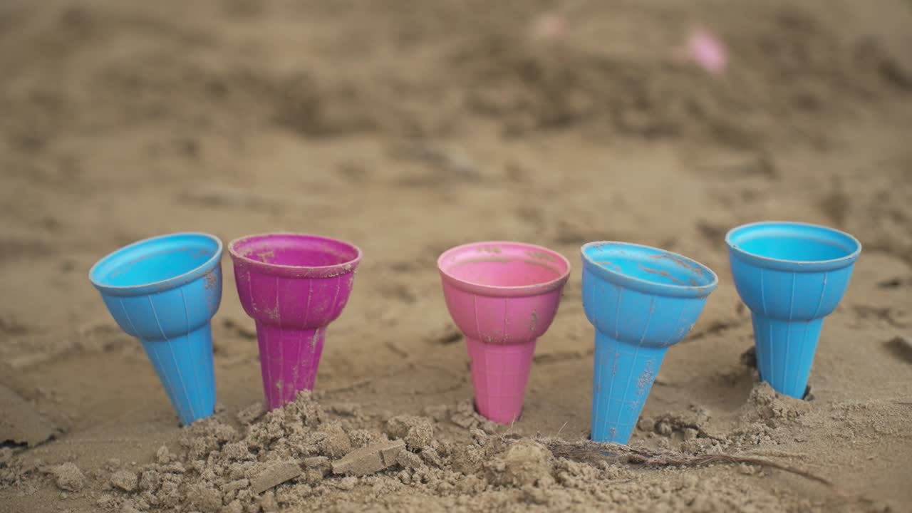 모래 속 에 있는 다채로운 장난감 컵 들