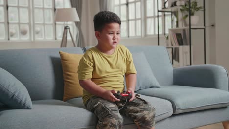 extremely happy successful boy becoming win, making sign of winner with his hand, while holding his joystick