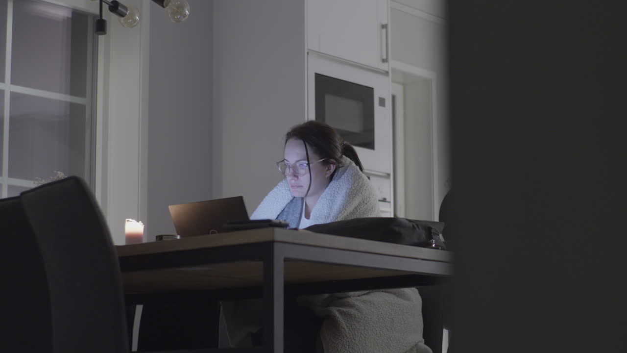 Donna attraente in vestaglia che studia a tarda notte sul tavolo della cucina.