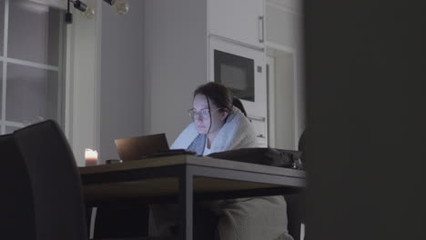 Attractive-woman-wearing-robe-studying-late-night-on-kitchen-table