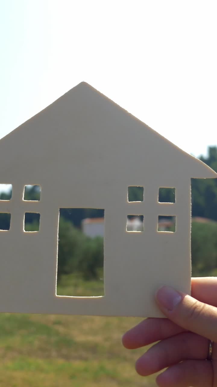 A model house held up in front of a background