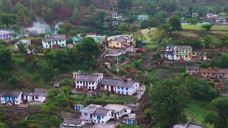aerial drone shot of a village tucked away in a deep valley, surrounded by rugged cliffs.