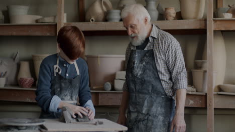 young apprentice learning pottery from an experienced master