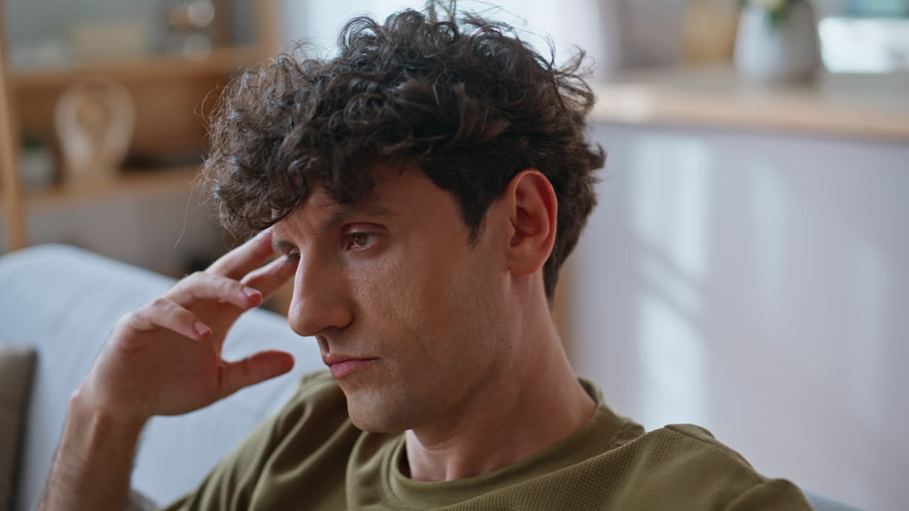 Bored guy watching tv in modern living room sofa closeup. Man feeling boredom