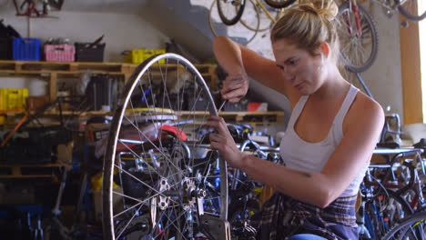 mujer reparando una bicicleta en un taller 4k