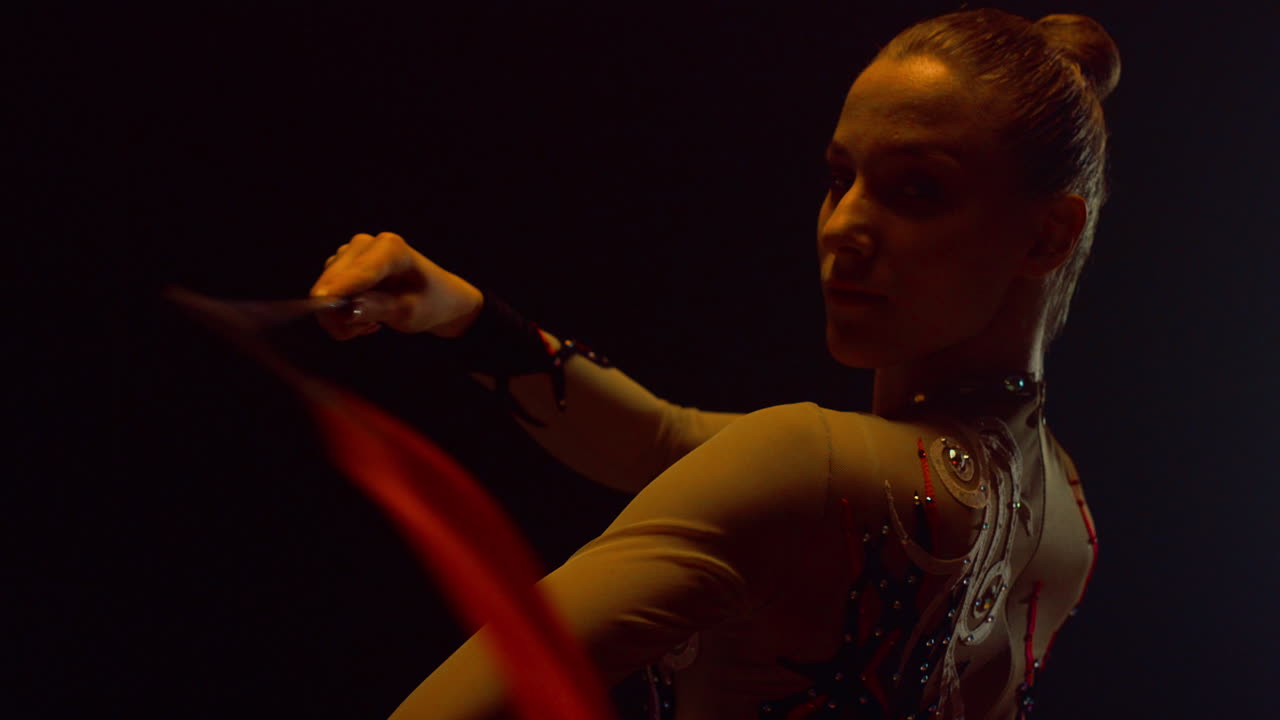 una bonita gimnasta de pie con una cinta. una chica practicando gimnasia rítmica en el interior