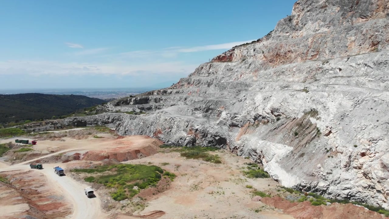 Un paisaje de cantera con vehículos circulando por caminos de tierra. El terreno rocoso y los cielos despejados crean un entorno accidentado. Adecuado para contenido industrial o geológico.