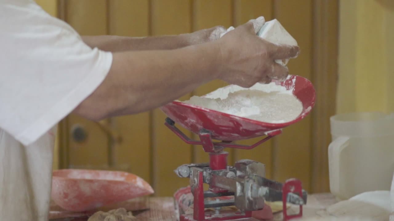 una persona que opera una prensa de tortillas en una panadería para preparar masa para tortillas o panes planos