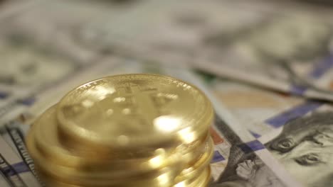 pile of golden bitcoin coins rotating above 100 us dollar paper bills close up shot