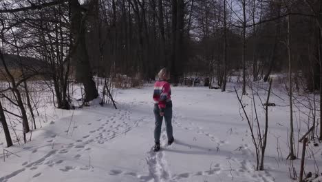 Low-flying-aerial-shot-following-happy-blonde-girl-around-in-charming-forest