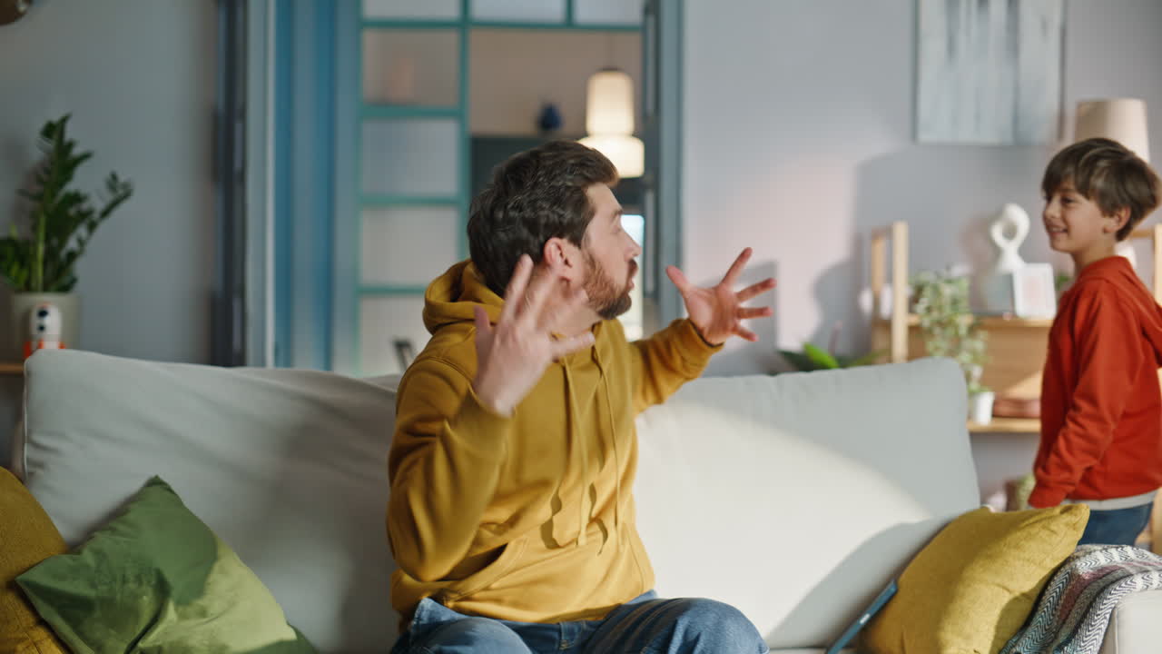 Noisy child bothering father talking cellphone sitting home sofa closeup